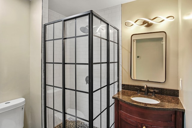 bathroom featuring a tile shower, vanity, and toilet