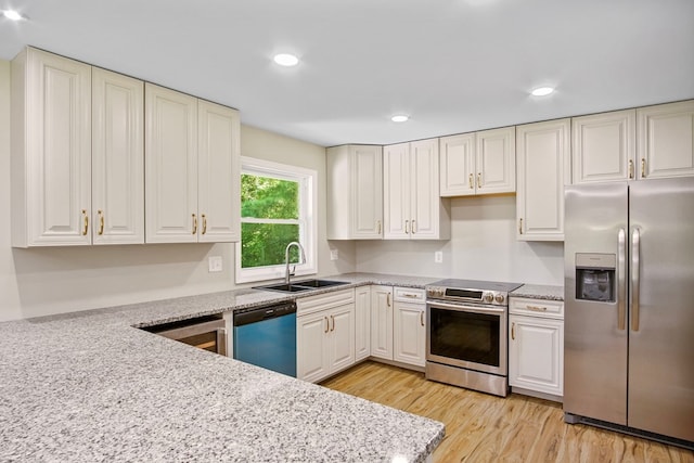 kitchen with light stone counters, sink, light hardwood / wood-style floors, and appliances with stainless steel finishes