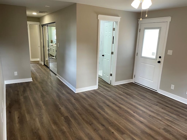 foyer entrance with dark wood-type flooring, visible vents, and baseboards