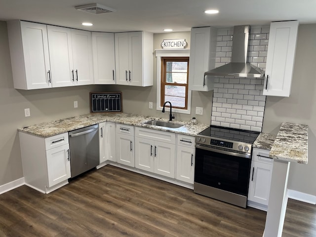 kitchen with wall chimney range hood, stainless steel appliances, sink, and white cabinets