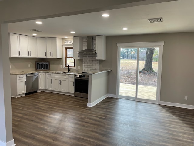 kitchen with wall chimney range hood, sink, dark wood-type flooring, white cabinetry, and stainless steel appliances