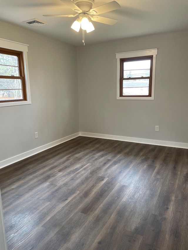 unfurnished room featuring a ceiling fan, dark wood-style flooring, visible vents, and baseboards