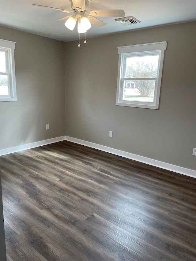 spare room with visible vents, dark wood finished floors, baseboards, and ceiling fan
