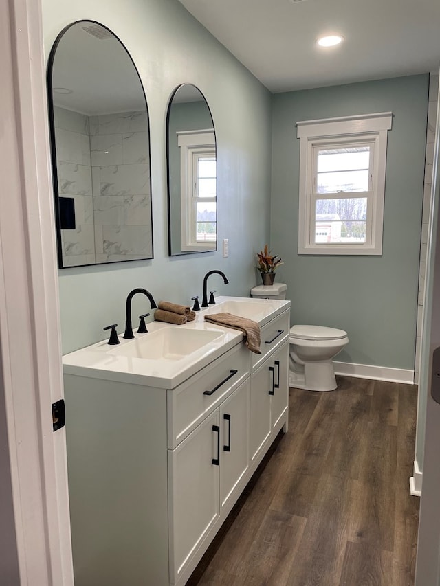 bathroom with a wealth of natural light, baseboards, toilet, and wood finished floors
