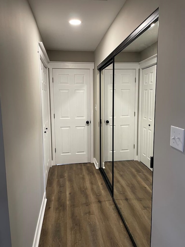 corridor with dark wood-type flooring and baseboards