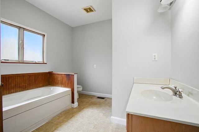 bathroom featuring visible vents, toilet, baseboards, a bath, and vanity