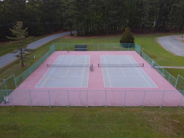 view of tennis court with fence and a lawn