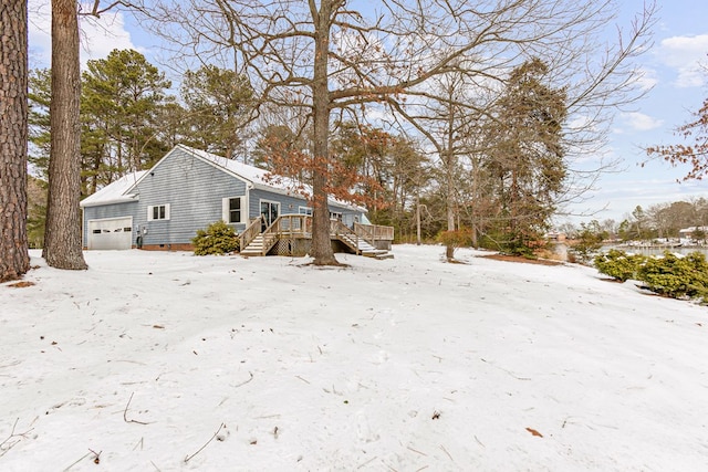 view of snowy exterior featuring crawl space, a deck, and a garage