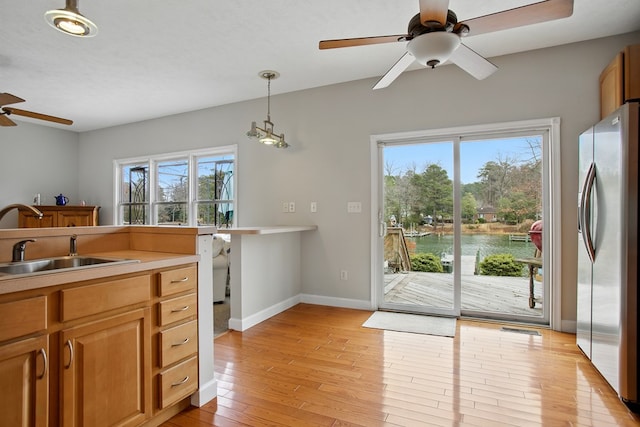 kitchen featuring a healthy amount of sunlight, light wood-type flooring, stainless steel fridge, a ceiling fan, and a sink