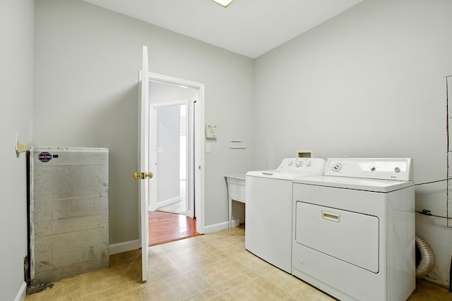 clothes washing area featuring washing machine and clothes dryer, laundry area, and baseboards