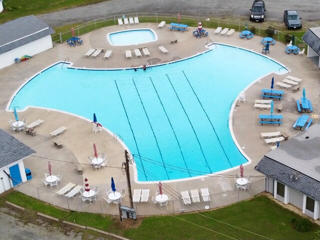 community pool with a patio area and fence