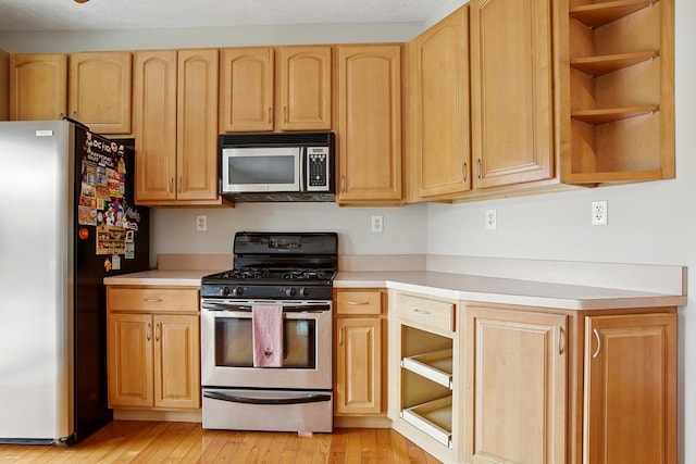 kitchen with light brown cabinetry, stainless steel appliances, light countertops, and open shelves