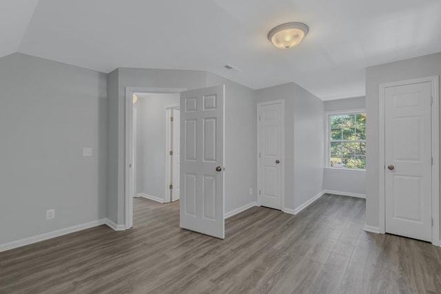 additional living space featuring vaulted ceiling and light hardwood / wood-style flooring