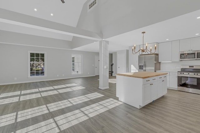 kitchen with appliances with stainless steel finishes, a notable chandelier, a center island, light hardwood / wood-style floors, and white cabinetry