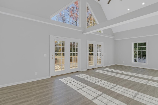 empty room with light hardwood / wood-style flooring, high vaulted ceiling, and ceiling fan