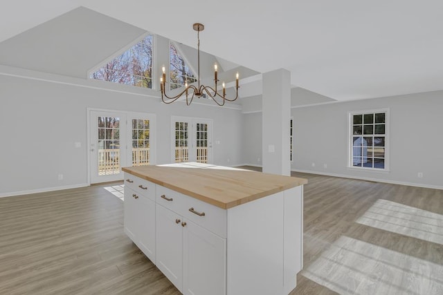 kitchen featuring a center island, white cabinets, hanging light fixtures, butcher block countertops, and a notable chandelier