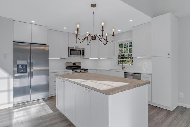 kitchen with appliances with stainless steel finishes, sink, decorative light fixtures, white cabinets, and a kitchen island