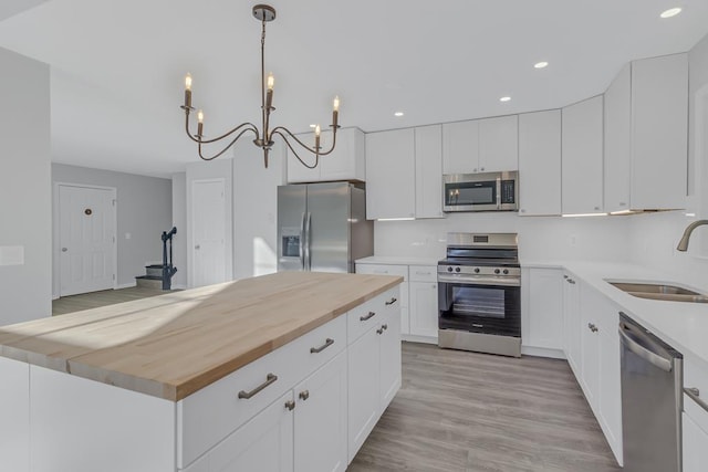 kitchen with white cabinets, pendant lighting, stainless steel appliances, and sink