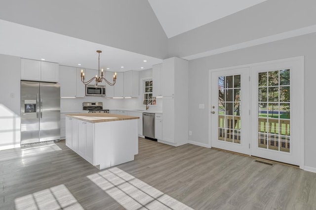 kitchen featuring a center island, hanging light fixtures, high vaulted ceiling, white cabinets, and appliances with stainless steel finishes