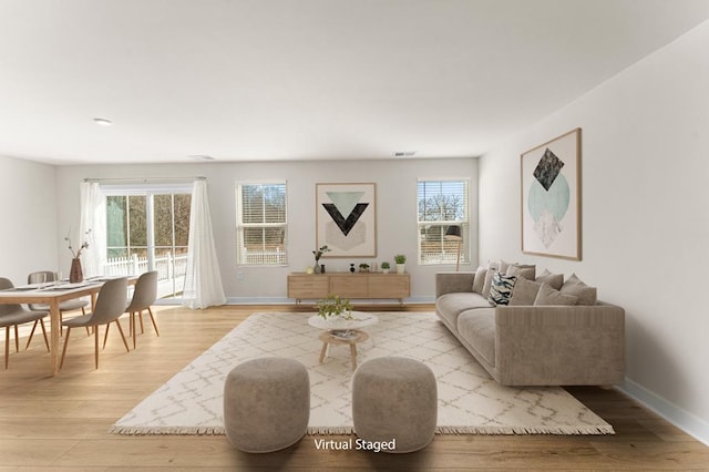 living room with visible vents, baseboards, and light wood-style floors