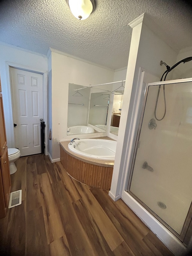 bathroom featuring shower with separate bathtub, a textured ceiling, toilet, and wood-type flooring