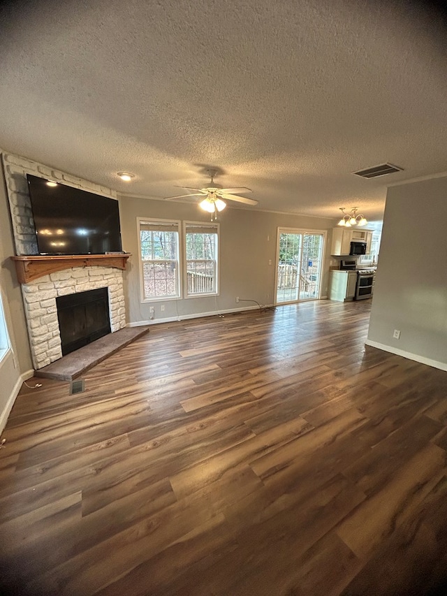 unfurnished living room with a textured ceiling, a stone fireplace, ceiling fan, and dark hardwood / wood-style floors