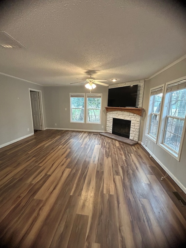 unfurnished living room with ornamental molding, a textured ceiling, ceiling fan, dark wood-type flooring, and a fireplace