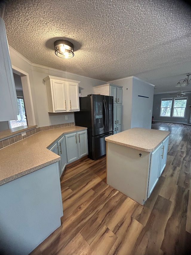 kitchen with dark hardwood / wood-style flooring, black fridge, white cabinetry, and crown molding