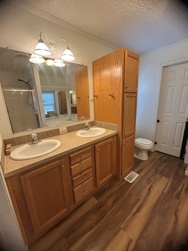 bathroom featuring vanity, a textured ceiling, a shower with door, wood-type flooring, and toilet