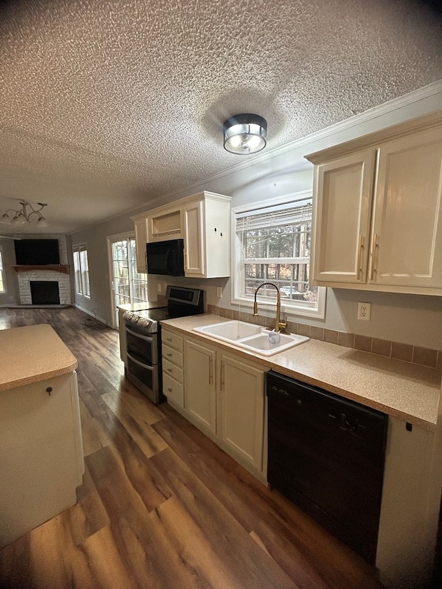 kitchen with black appliances, crown molding, sink, a brick fireplace, and dark hardwood / wood-style floors