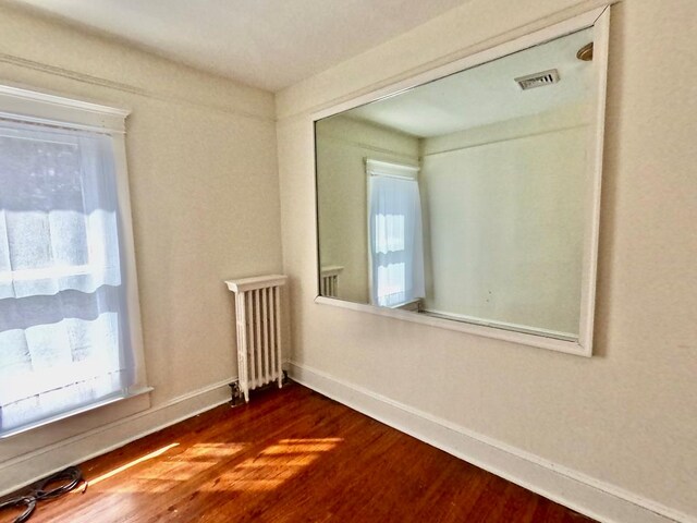 unfurnished room featuring dark hardwood / wood-style floors, radiator, and ceiling fan