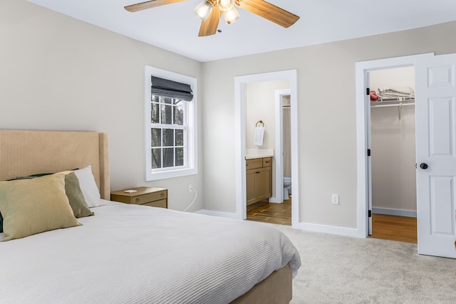 bedroom featuring light carpet, baseboards, ensuite bathroom, a spacious closet, and a closet