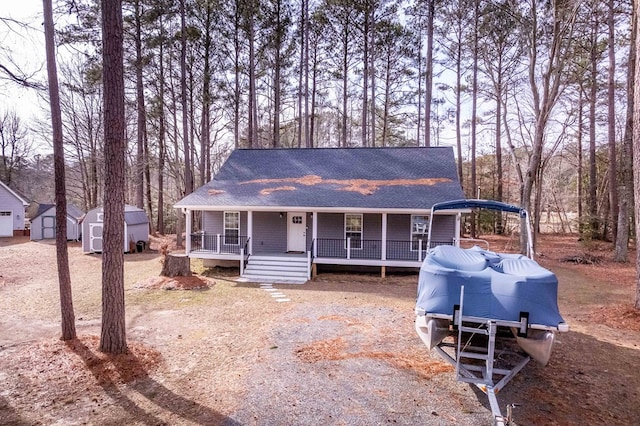 view of front of home with a shed, roof with shingles, a porch, and an outdoor structure