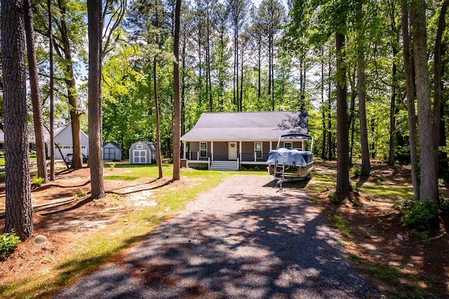 146 Portal Dr, Montross, VA 22520 - view of front facade with a storage shed, a porch, an outdoor structure, gravel driveway, and view of wooded area