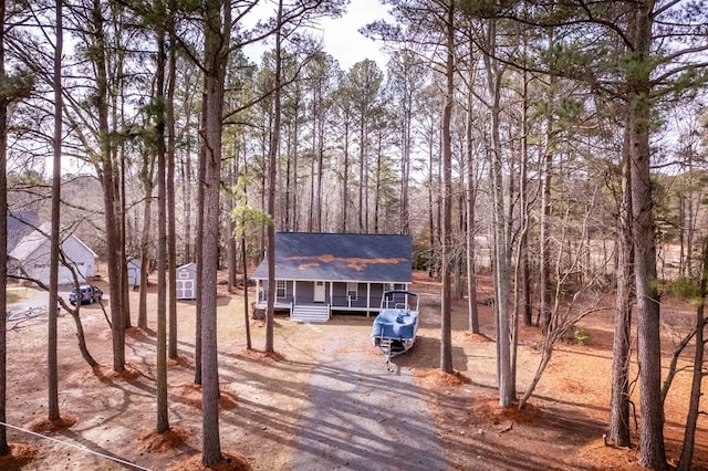 rustic home with covered porch, roof with shingles, and driveway