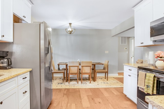 kitchen featuring appliances with stainless steel finishes, light wood-style floors, white cabinetry, and light stone countertops