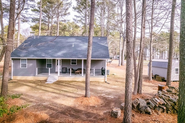 back of house featuring covered porch and roof with shingles