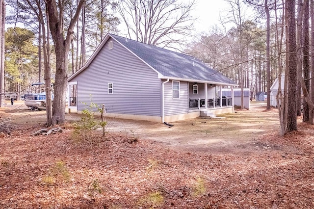 view of side of home featuring a porch and a shingled roof