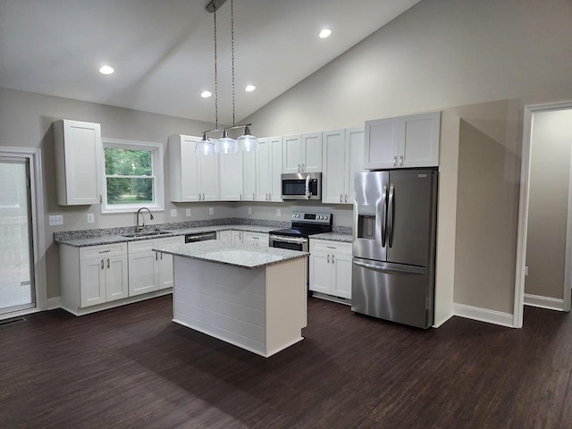 kitchen with appliances with stainless steel finishes, sink, decorative light fixtures, white cabinets, and a center island