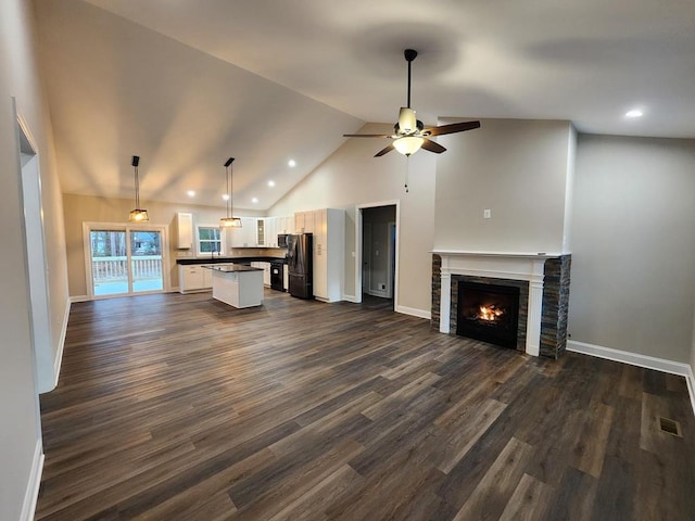 unfurnished living room featuring a stone fireplace, ceiling fan, high vaulted ceiling, and dark hardwood / wood-style floors