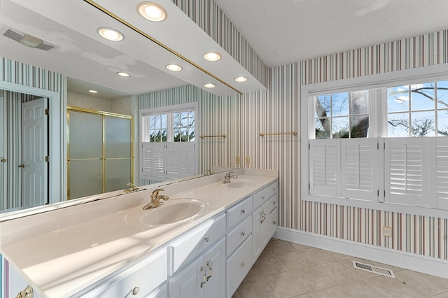 bathroom featuring tile patterned floors, vanity, an enclosed shower, and a textured ceiling