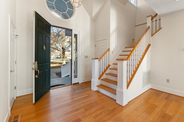 foyer entrance featuring a high ceiling, a textured ceiling, and light hardwood / wood-style floors