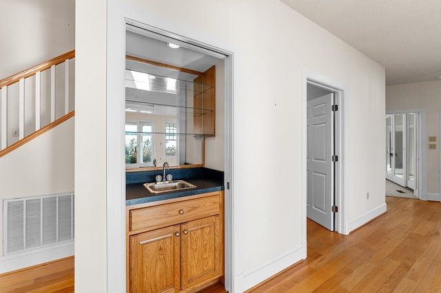 bar featuring sink and light hardwood / wood-style floors