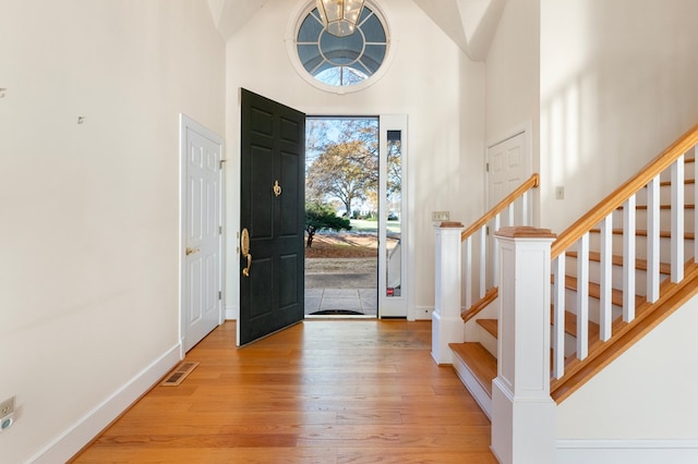 entrance foyer with high vaulted ceiling and light hardwood / wood-style floors