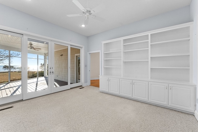 carpeted empty room featuring french doors, a textured ceiling, and ceiling fan