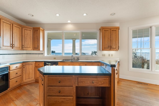 kitchen featuring a center island, sink, oven, and light wood-type flooring