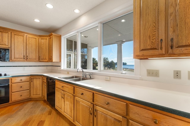 kitchen with sink, black appliances, and light wood-type flooring