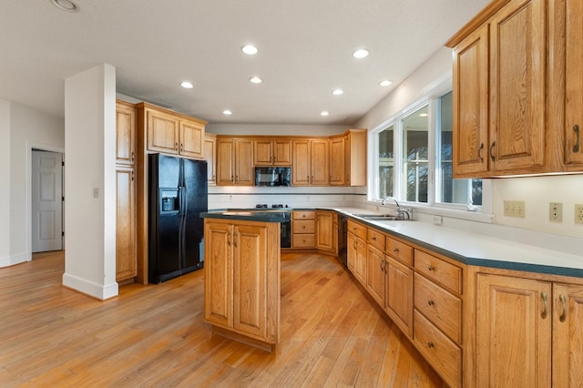 kitchen featuring sink, light hardwood / wood-style flooring, a kitchen island, and black appliances