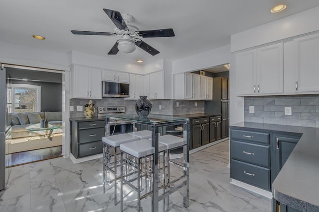 kitchen with tasteful backsplash, ceiling fan, blue cabinets, and white cabinetry