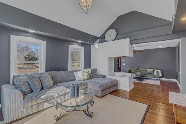 living room with ceiling fan with notable chandelier, hardwood / wood-style floors, and vaulted ceiling